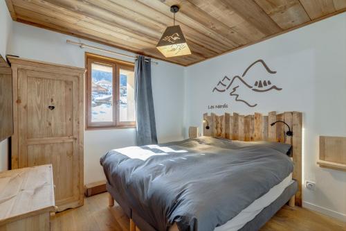 1 dormitorio con 1 cama en una habitación con techos de madera en Les Nards, en Praz-sur-Arly