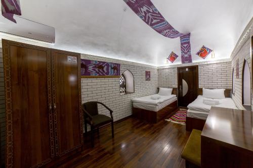 a room with two beds and a table in it at Feruzkhan Hotel - Madrassah Mohammed Rakhim Khan 1871 in Khiva
