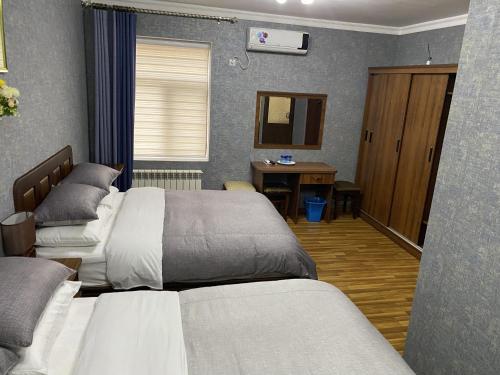 a bedroom with two beds and a desk in it at Cinzano Complex in Samarkand