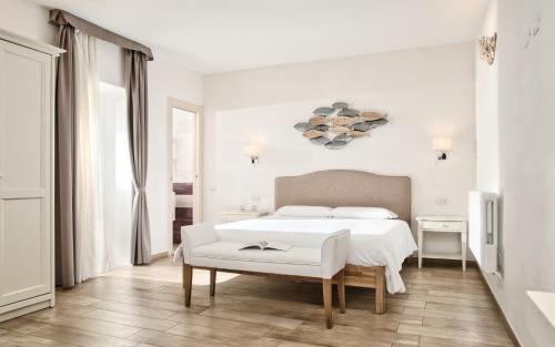 a white bedroom with a white bed and a table at Smart Suite & Apartments in Santa Teresa Gallura