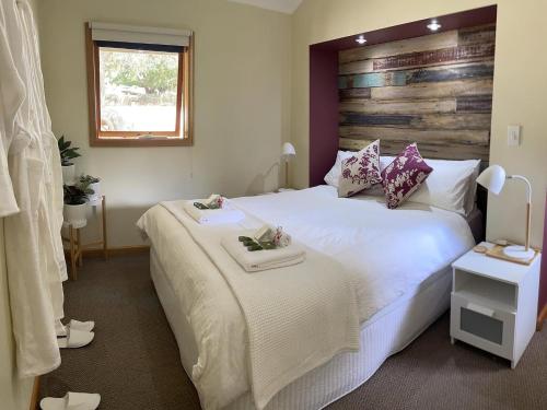 Schlafzimmer mit einem großen weißen Bett mit einem Kopfteil aus Holz in der Unterkunft The Mulberry Cottage in The Patch