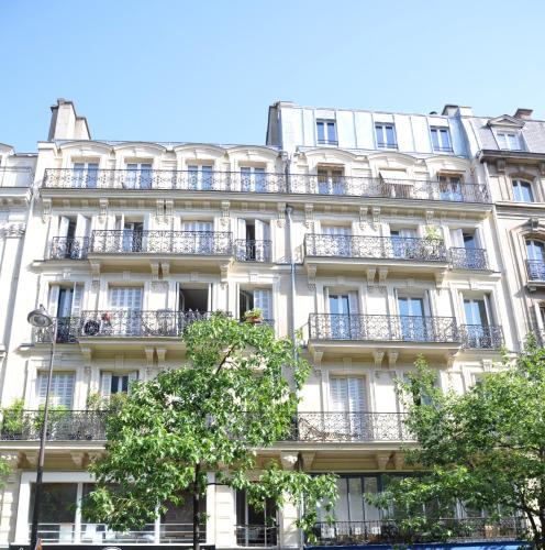 - un grand bâtiment blanc avec des balcons et des arbres devant dans l'établissement Plein centre, à Paris