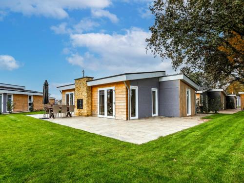 a house with a patio and a lawn at Holiday Home Green Resort Mooi Bemelen by Interhome in Bemelen