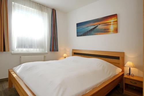 um quarto com uma cama branca e uma janela em Strandstraße 16 Wohnung 14 em Kühlungsborn