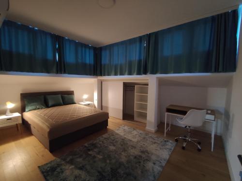 a bedroom with a bed and a desk and windows at Blue Apartment Riverside in Podgorica