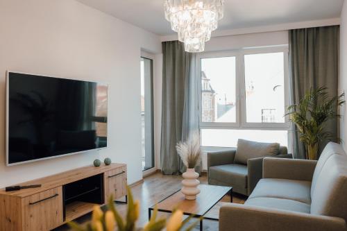 uma sala de estar com uma televisão grande e um sofá em Złote Apartamenty 58 em Legnica