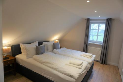 a bedroom with a large bed with white sheets and pillows at Lerchenhof - Haus Kiebitz in Reestow