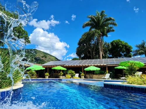 a pool at a resort with green umbrellas at Pousada Maritacas do Sana in Sana