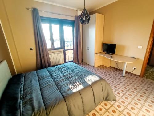 a bedroom with a bed and a desk and a window at Casa Malù in Fiumicino