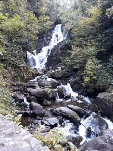 a waterfall on the side of a river with rocks at Cosy Holidayhomes Kerry in Kenmare