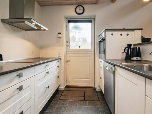 una cocina con una puerta y un reloj en la pared en 5 person holiday home in Millinge, en Millinge