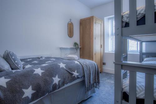 a bedroom with a bed with a gray blanket with stars at Hawtree Cottage - 2 Bedroom Cottage - Tenby in Tenby