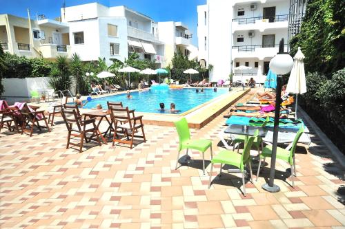 a pool with tables and chairs and people in a building at Santa Marina Hotel Apartments in Kos