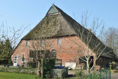 un grand bâtiment en briques rouges avec un toit de chaume dans l'établissement De Olle Uhlhoff, à Barlt