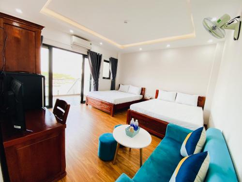 a hotel room with two beds and a couch at Khách sạn Ngọc Hồi in Quy Nhon