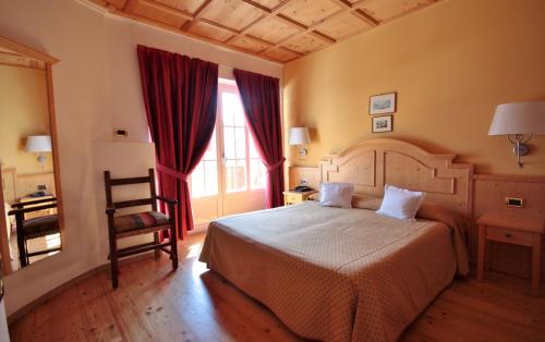 a bedroom with a large bed and a chair at Hotel La Meridiana in Madesimo