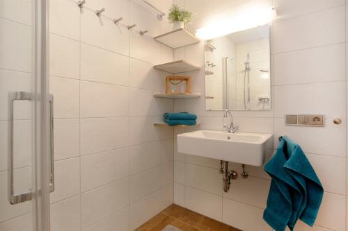 ein weißes Badezimmer mit einem Waschbecken und einem Spiegel in der Unterkunft Quartier Bergzeit 1 in Stryck