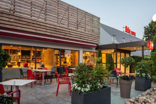 een restaurant met rode stoelen en tafels ervoor bij ibis Nuits Saint Georges in Nuits-Saint-Georges