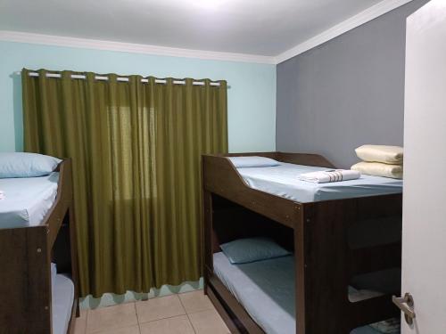 Zimmer mit 2 Etagenbetten und einem grünen Vorhang in der Unterkunft 10 MIN AEROPORTO GUARULHOS in Guarulhos
