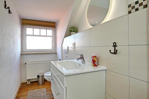 Villa Hanse Wohnung 320 في كولونغسبورن: حمام أبيض مع حوض ومرحاض