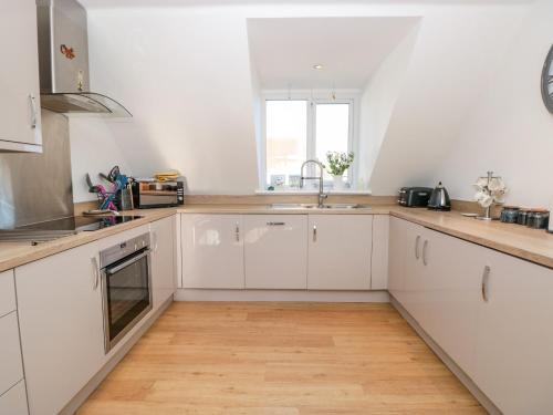 a kitchen with white cabinets and a wooden floor at Seaspray in Dartmouth