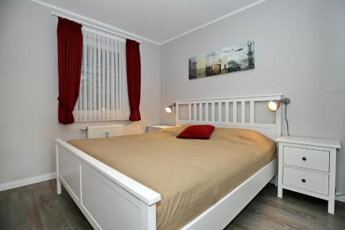 1 dormitorio con cama blanca y almohada roja en Meeresblick Wohnung 112, en Kühlungsborn