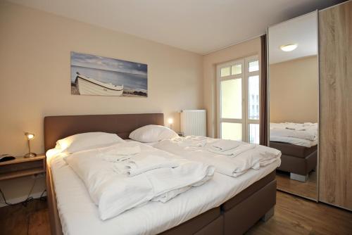 um quarto com uma cama grande e lençóis brancos em Villa Hanse Wohnung 312 em Kühlungsborn
