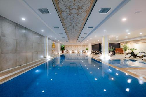a swimming pool in a hotel with a ceiling at Somerset City Centre Atyrau in Atyraū