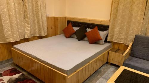 a wooden bed with pillows and a chair in a room at Tulip Flowing River View Hotel. in Shamshi
