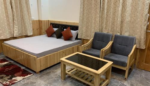 a bedroom with a bed and two chairs and a table at Tulip Flowing River View Hotel. in Shamshi