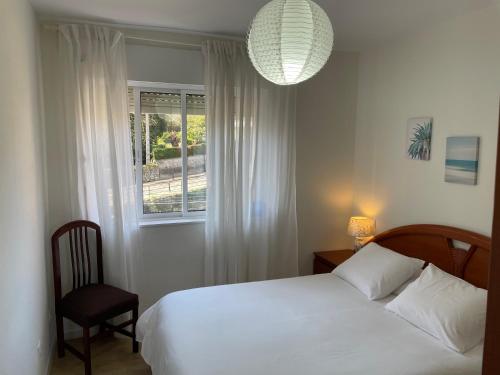 1 dormitorio con cama blanca y ventana en Apartamento Excelentes vistas a la Ria, Wifi y Parking, en San Vicente de la Barquera
