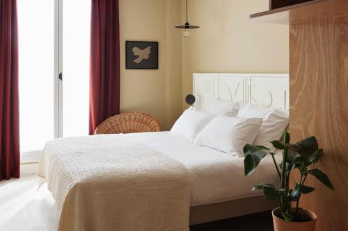 une chambre avec un lit avec des draps blancs et une plante dans l'établissement Hotel Orphée - Orso Hotels, à Paris