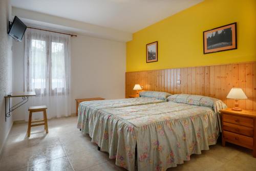 a bedroom with a bed and a yellow wall at Hostal Kimboa in Ansó