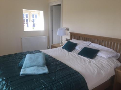 um quarto com uma cama grande e toalhas azuis em Cosy getaway near Rutland Water em Oakham