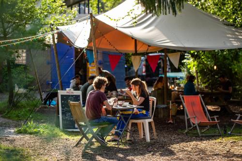 two people sitting at a table under an umbrella at Arkeo - Luxury tents and cabins at the river in Nonceveux