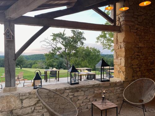 a patio with tables and chairs and a stone wall at Domaine de Cazal - Chambres d'Hôtes avec piscine au cœur de 26 hectares de nature préservée in Saint-Cyprien