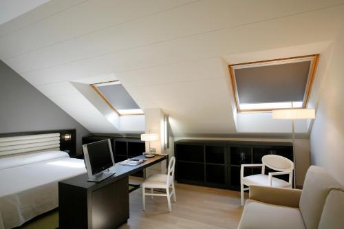 a bedroom with a bed and a desk with a computer at Hotel Bienestar Moaña in Moaña