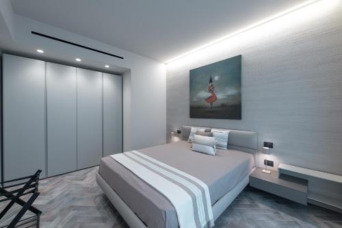 a white bedroom with a bed and a painting on the wall at Villa Arianna Acireale in Acireale