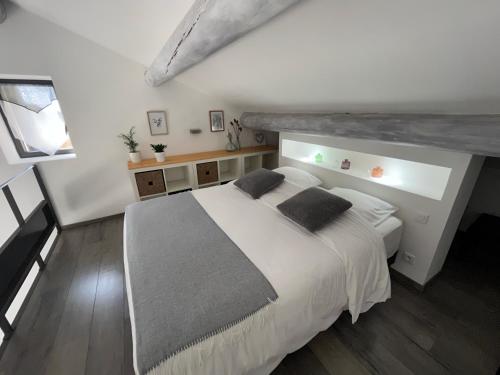 1 dormitorio con 1 cama blanca grande y 2 almohadas en Gîtes dans Mas en pierres, en Robion en Luberon