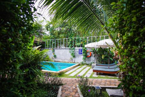 a backyard with a swimming pool and a palm tree at Capricorn Village - SHA Extra Plus in Patong Beach