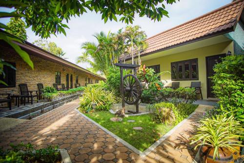 a garden in front of a house with a statue at Capricorn Village - SHA Extra Plus in Patong Beach