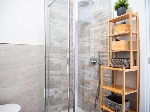 La salle de bains est pourvue d'une douche et d'une étagère en bois. dans l'établissement The Best Rent - Apartment near Arco della Pace, à Milan