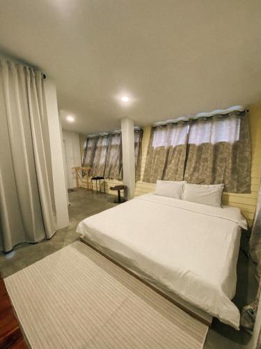 a bedroom with a large white bed and windows at ฮักเคียงโขง HUG Khieng Khong Nongkhai Hostel in Nong Khai