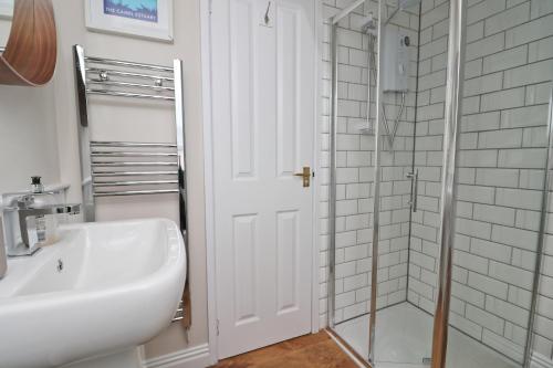a white bathroom with a sink and a shower at BY THE BEACH cottage, dogs welcome in Saint Merryn