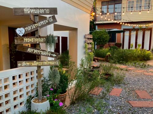 a sign in a garden in front of a building at ฮักเคียงโขง HUG Khieng Khong Nongkhai Hostel in Nong Khai