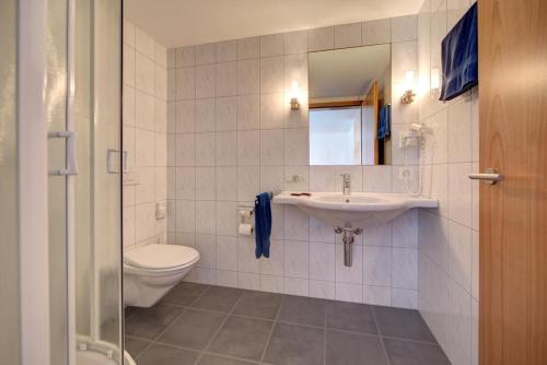 a bathroom with a sink and a toilet and a mirror at Gasthaus Rössli in Brülisau
