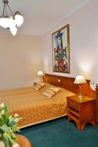 a bedroom with a bed and a painting on the wall at Hotel Kolonada in Karlovy Vary