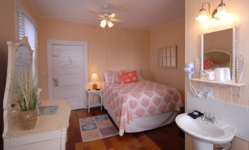 a bedroom with a bed and a sink and a mirror at Inkwell Beach Cottage in Oak Bluffs