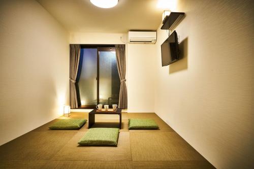 a room with a table and a television and green mats at Rikyuan Kyoto Nishikyogoku room A in Kyoto
