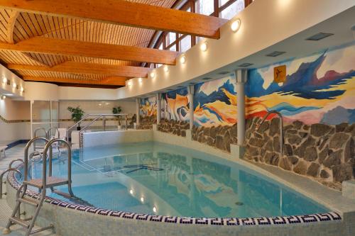 uma piscina num hotel com uma pintura na parede em Hotel Kolonada em Karlovy Vary